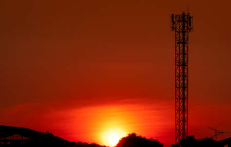 Beautiful red and orange sunset sky. Silhouette telecommunication tower and  tree in the evening...