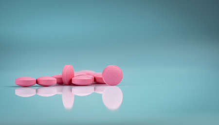 Round pink tablets pill on gradient background. Vitamins and minerals plus folic acid vitamin E and zinc in drug bottle on gradient background. Pink tablets pills for during and after pregnancy woman.の写真素材