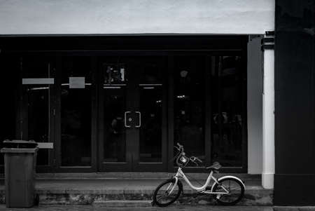 Bike for rent parked on concrete floor in front of office building. Bicycle for city tour. Abandoned bike parked near recycle bin. Eco-friendly transport.  Bicycle for rent by mobile application.の写真素材