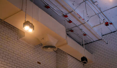 Ceiling lamp with opened light and air duct hanging on ceiling. Air conditioner pipe system. Air...
