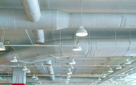 Air duct, air conditioner pipe, wiring pipe, and fire sprinkler system. Air flow and ventilation system. Building interior. Ceiling lamp light with opened light. Interior architecture concept.の写真素材