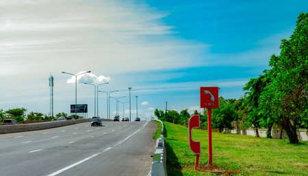 Emergency SOS telephone installed at roadside. Highway SOS call box. Motorway emergency roadside call system. Emergency phone for help people had car accident on highway. Car driving on asphalt road.の写真素材