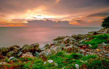 Rocks on stone beach at sunset. Beautiful beach sunset sky. Twilight sea and sky. Tropical sea at dusk. Romantic sky and clouds. Calm and relax life. Nature landscape. Tranquil and peaceful concept.の写真素材