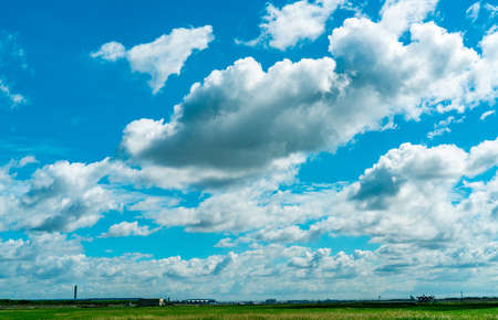 Landscape green grass field and wire fence of the airport and beautiful blue sky and white fluffy clouds. Nice weather. Nature landscape. Area around the airport. Fence for safety. Airport building.の写真素材