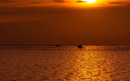 Beautiful sunset over the sea. Dark and golden sunset sky and clouds. Nature background for tranquil and peaceful concept. Orange sunset sky. Art picture of sky at dusk. Twilight sky in the evening.の写真素材