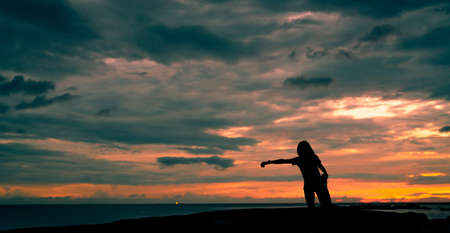 Silhouette woman workout in the morning at stone beach with beautiful sunrise sky. Fit woman runner ...