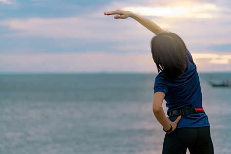 Silhouette woman workout in the morning at stone beach with beautiful sunrise sky. Fit woman runner ...