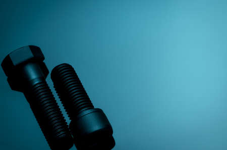 Metal bolts on blue background. Hardware tools. Closeup hex head bolt and socket cap bolt with copy...