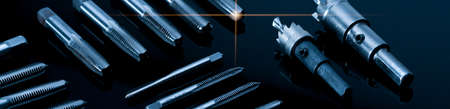 Closeup straight flute tap tip and hole saw on dark background.  Industrial tapping tools. Carbide...