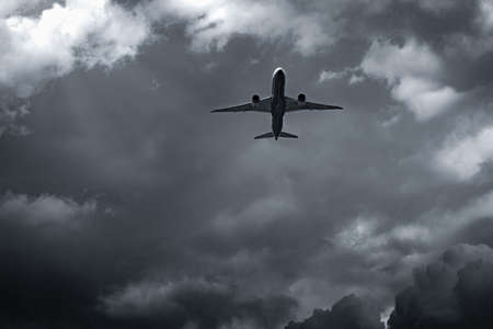 Airplane flying on dark sky and white clouds.の写真素材
