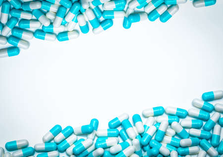 Blue-white antibiotic capsule pills on white background. Antibiotic drug resistance concept. Pharmaceutical industry. Antimicrobial medicine. Pharmacy product. Drug pills frame for health information.の写真素材