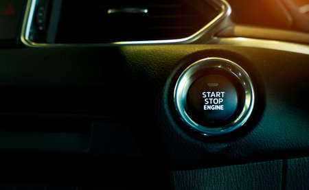 Start stop engine button of luxury car. Push up button for start or stop car engine in keyless automobile. Turn key with ignition system concept. Black ignition switch. Car dashboard interior view. の写真素材
