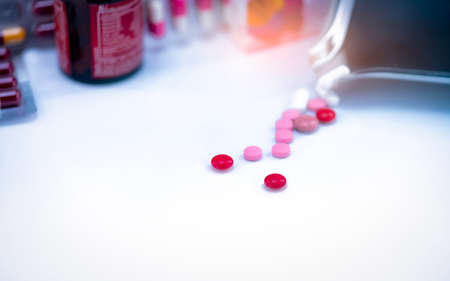 Red tablets pills on blurred background of tablets, stainless steel drug tray, and vitamin bottle. Pharmaceutical industry. Pharmacy drugstore products. Healthcare and medicine concept. Pharmaceutics.の写真素材