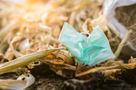 Used face mask discard in household garbage. Medical waste disposal with unhygienic management. Contaminated waste in community. Disposable earloop face mask waste garbage on floor. Coronavirus impactの写真素材