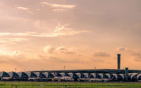 BANGKOK, THAILAND-JUNE 2, 2020 : Thai Airways airplane parked at apron in Suvarnabhumi airport. Modern passenger terminal of the airport and air traffic control tower with sunset sky background.のeditorial素材