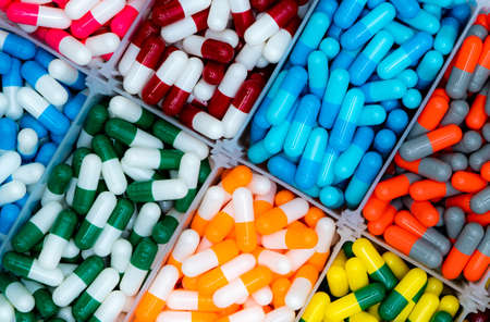 Top view of antibiotic capsule pills in plastic tray. Antibiotic drug resistance. Pharmacy products. Healthcare and medicine. Full frame of red, blue, green, yellow, orange, and gray capsule pills.の写真素材