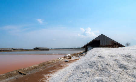 Landscape of brine salt farm with blue sky on sunny day. Salt warehouse. Pile of organic sea salt....