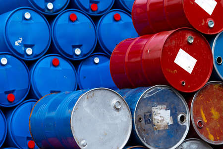 Old chemical barrels. Blue and red oil drum. Steel and plastic oil tank. Toxic waste warehouse. Hazard chemical barrel with warning label. Industrial waste in drum. Hazard waste storage in factory.の写真素材