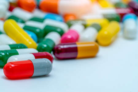 Selective focus on orange-gray antibiotic capsule pill on blurred background of colorful capsule...