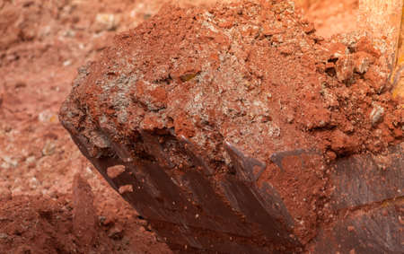Backhoe working by digging soil at construction site. Bucket of backhoe digging soil. Crawler...