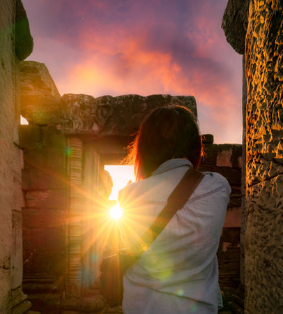 Rearview of woman photographer travel in Phimai Historical Park with sunset sky. Landmark of Nakhon Ratchasima, Thailand. Travel destinations. Historic site is ancient. Ancient building. Khmer temple.の写真素材