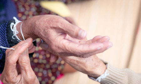 The ceremony of binding elderly people's wrist with the holy thread to console old people's Kwan. Thai culture. Beliefs and local culture of Northeastern Thai people. Aging society in Southeast Asia.の写真素材