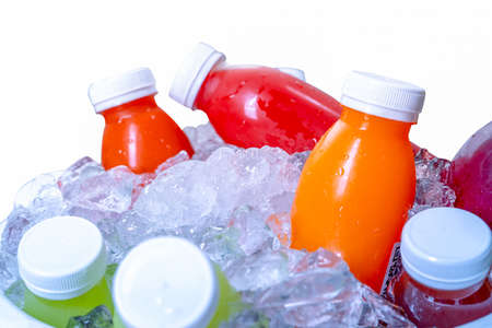 Organic cold pressed raw vegetable and fruit juice bottle in crushed ice bucket on white background....
