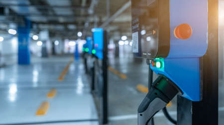 Blurred electric car charging station for charge EV battery. Plug for vehicle with electric engine. EV charger. Clean energy. Charging point at car parking lot. Future transport technology.の写真素材