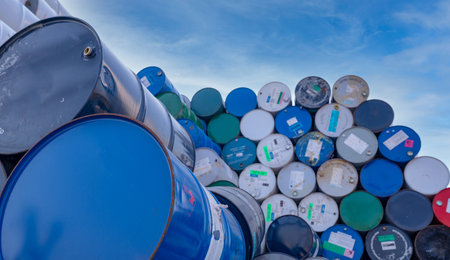 Old chemical barrels. Big stack of blue oil drum against sky. Steel oil tank. Toxic waste warehouse. Hazard chemical barrel with warning label. Industrial waste. Empty chemical barrels in factory.の写真素材