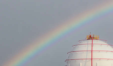 Industrial gas storage tank with rainbow sky background. LNG or liquefied natural gas storage tank. Gas reservoirs in petroleum refinery. Above-ground storage tank. Natural gas storage industry.の写真素材