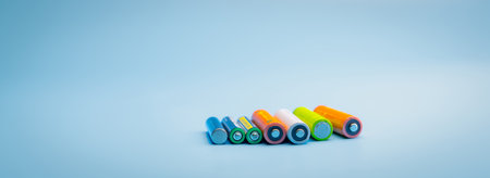 Rechargeable battery on blue background. Selective focus negative terminals of rechargeable lithium-ion batteries. AA and AAA size of old Li-ion battery. Battery recycling concept. Green power energy.の写真素材