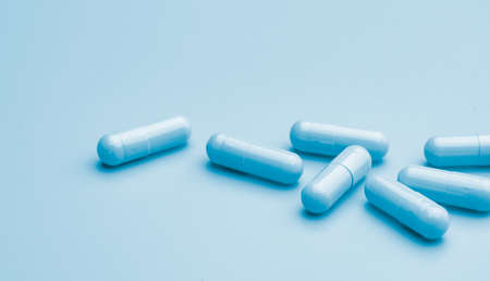 Blue capsule pills on blue background. Online pharmacy banner. Group of capsule pills....