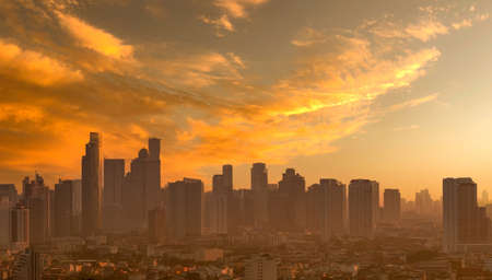Air pollution. Smog and fine dust of pm2.5 covered city in the morning with orange sunrise sky. Cityscape with polluted air. Dirty environment. Urban toxic dust. Unhealthy air. Urban unhealthy living.の写真素材