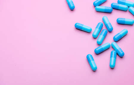Blue capsule pills on pink background. Blue capsule pills with copy space. Pharmaceutical industry. Community pharmacy product. Drug use in pregnancy woman and lactation and elderly people topics.の写真素材