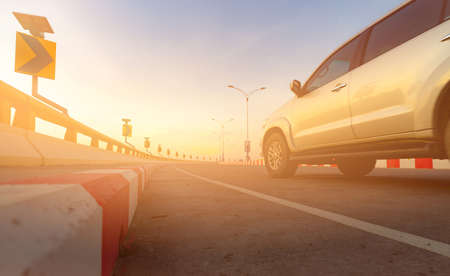 Motion blur of car driving on curve road with traffic sign. Road trip on summer vacation. Car drive on the street with sunset light. Summer travel by car. Solar panels energy on curve traffic sign.の写真素材