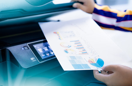 Office worker print paper on multifunction laser printer. Copy, print, scan, and fax machine in...