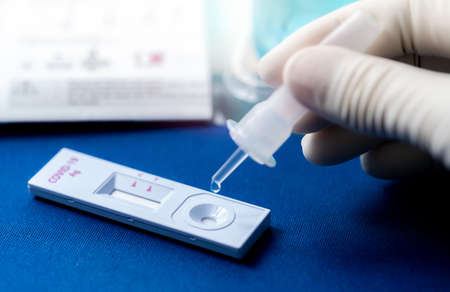 Hand holding sample tube and drops in the test device of covid 19 antigen self test. Antigen test kit for detection of coronavirus infection. Rapid antigen test. Coronavirus diagnosis. Medical device.の写真素材