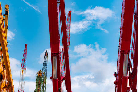 Crawler crane against blue sky and white clouds. Real estate industry. Red crawler crane use reel...