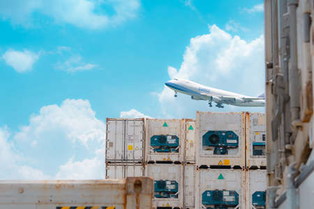 Cargo airplane flying above logistic container. Air logistic. Reefer for frozen food. Refrigerated container for export and import logistics. Freight transport. Aviation business. Merchandise export.のeditorial素材