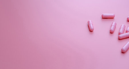 Pink capsule pills on pink background with copy space. Woman's health insurance and breast cancer concept. Vitamins and supplements for healthy skin. Pharmacy web banner. Online pharmacy background.の写真素材