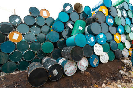 CHACHOENGSAO, THAILAND-JUNE 24, 2021 : Old chemical barrels stacked. Steel tank of plasticizer with label. Blue, green, black, and yellow chemicals barrels. Industrial drum. Hazard waste in factory.のeditorial素材