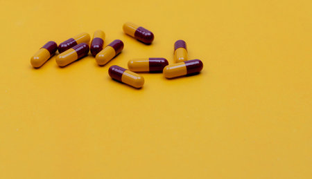 Red-yellow antibiotic capsule pills on yellow background. Prescription drug. Antibiotic drug resistance concept. Penicillin capsule pills. Pharmaceutical industry. Pharmaceutics. Pharmacy product.の写真素材