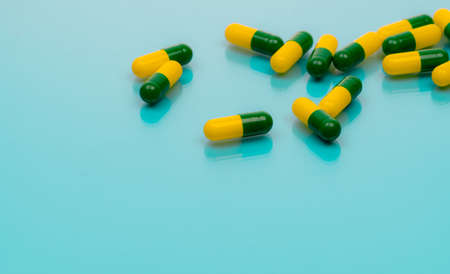 Tramadol pills. Green-yellow capsule pills on blue background. Tramadol is a strong painkiller medicine used to treat moderate to severe pain. Background for tramadol misuse topics. Opioids drug.の写真素材