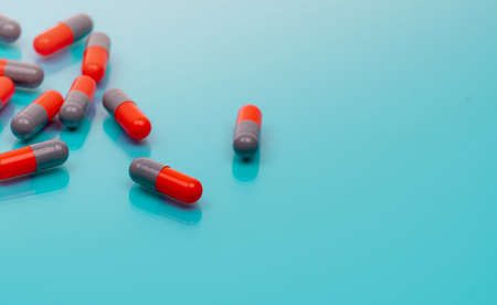 Orange and gray capsule pills on blue background. Pharmaceutical industry. Prescription drugs. Healthcare and medicine. Pharmacy web banner. New drug research and development. Health science.の写真素材