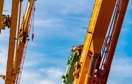 Selective focus on crawler crane against blue sky. Real estate industry. Red crawler crane use reel...