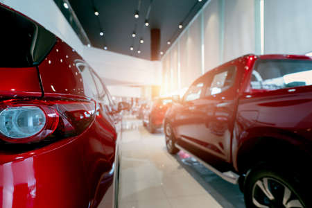 Rear view of red car parked in luxury showroom. Car dealership office. New car parked in modern showroom. Car for sale and rent business concept. Automobile leasing and insurance. Closeup tail light.の写真素材