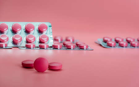Pink tablet pills and blister pack of pills on pink background. Prescription drug. Vitamins, minerals, and supplements concept. Pharmaceutical industry. Health care and medicine. Pharmacy product.の写真素材