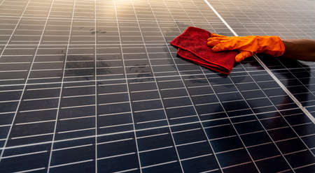 Cleaner cleaning solar panel on roof. Solar panel or photovoltaic module maintenance. Sustainable resource and renewable energy for go green. Solar power for green energy. Technology for future.の写真素材