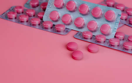 Pink tablet pills and blister pack of pills on pink background. Prescription drug. Vitamins, minerals, and supplements concept. Pharmaceutical industry. Health care and medicine. Pharmacy product.の写真素材