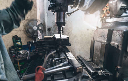 Selective focus on milling machine. Blurred worker is working on milling machine to milling metal plate. Tool for cut metal workpiece. Steel manufacturing factory. Milling process. Machine in workshopの写真素材